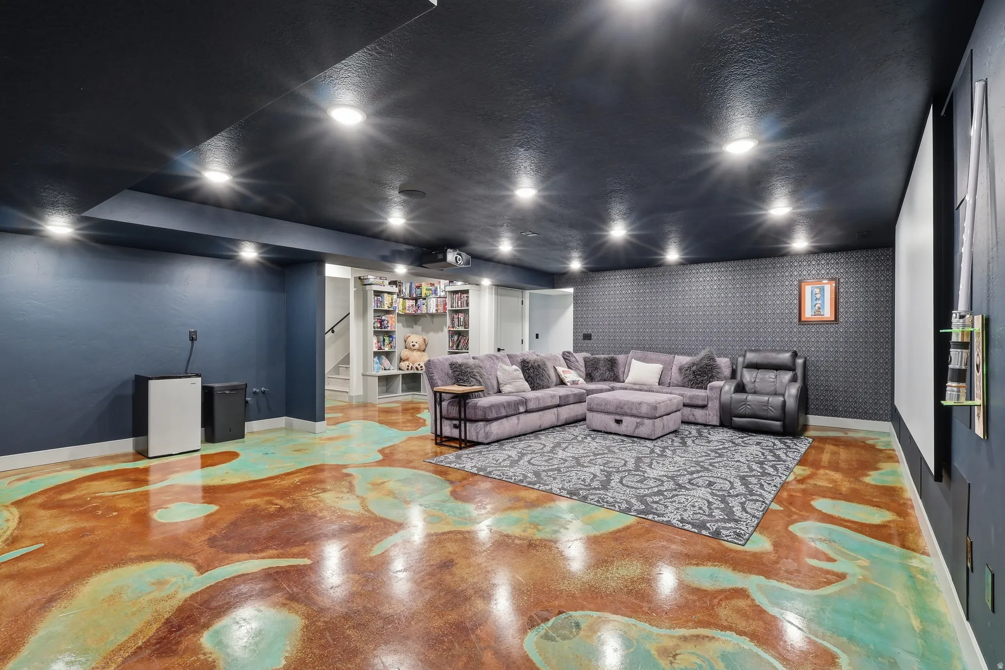 Home theater room featuring concrete floors and wallpapered walls