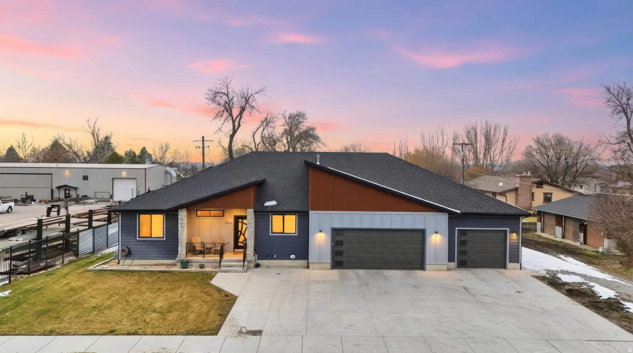 Contemporary home with driveway, board and batten siding, metal siding, a 4 car garage, jellyfish lighting  and covered porch