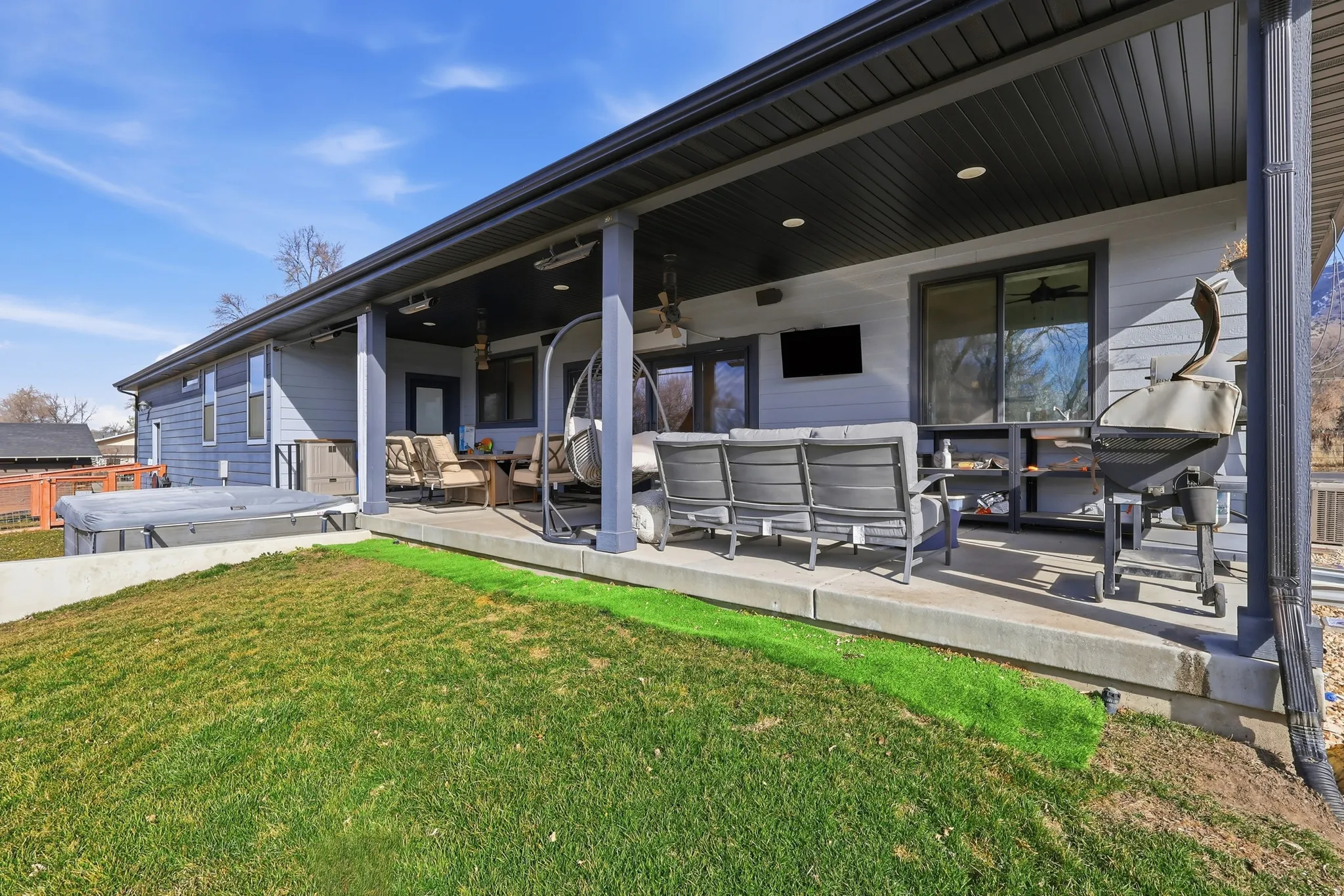 Rear view of property with outdoor furniture, a swim spa, a yard, and ceiling fan