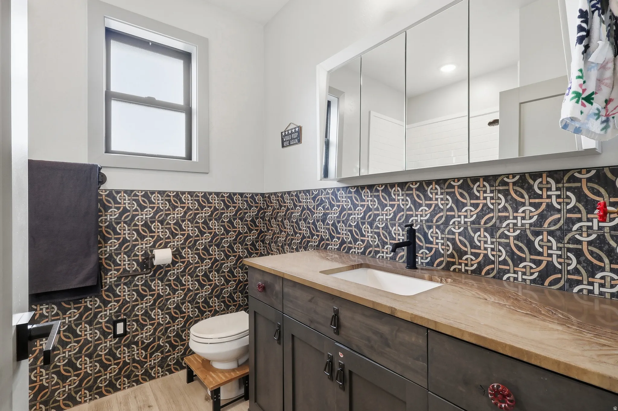 Full bathroom featuring vanity, light wood-style flooring, a wainscoted wall, and tile walls