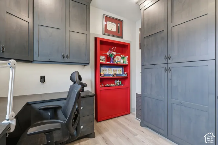 Home office with light wood finished floors.  Enter through the hidden door.