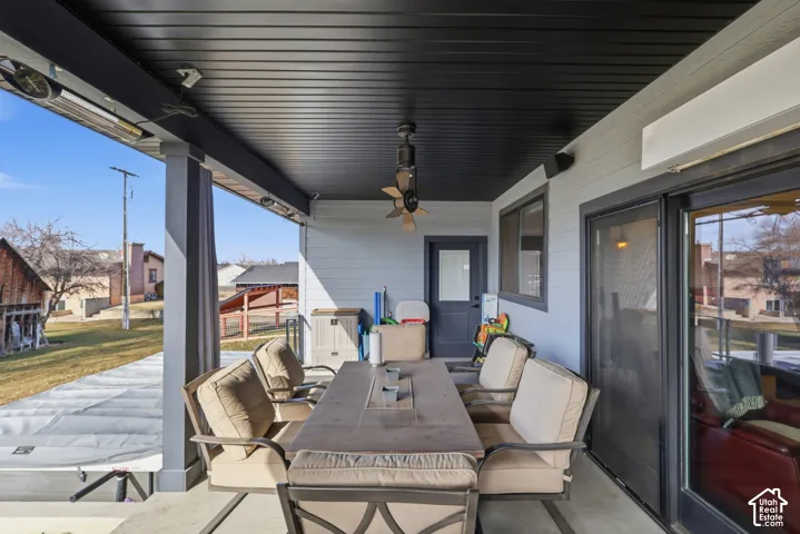 View of patio with outdoor dining area, ceiling fan, heaters, blower and a residential view