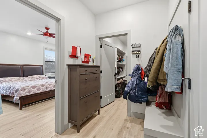 Drop zone with doggy door to garage light wood-type flooring and ceiling fan