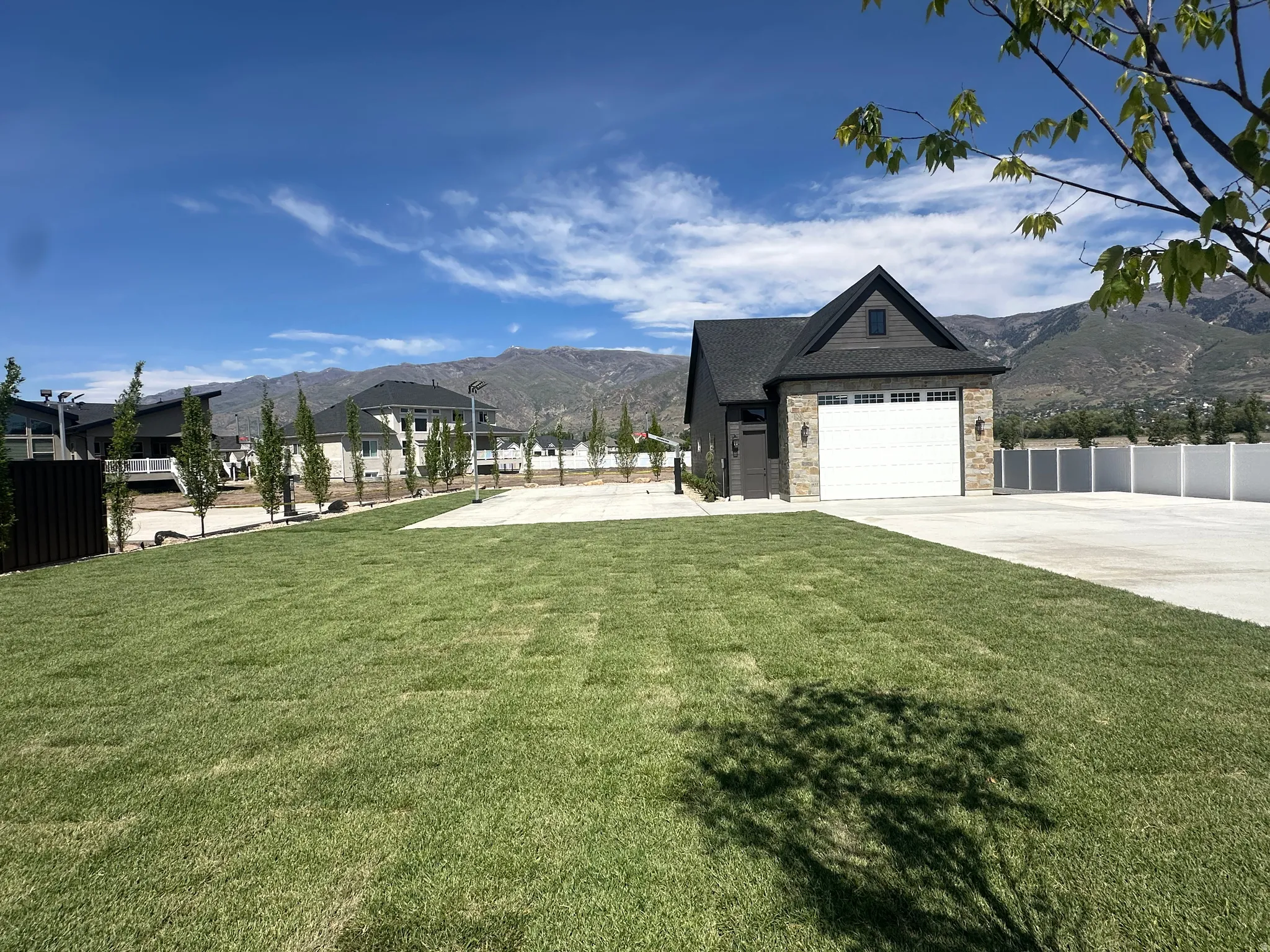 Expansive green lawn with mountain backdrop.   Sport court and garage