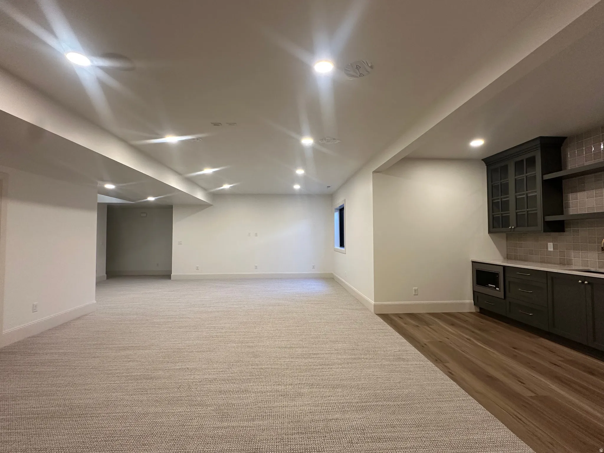 Finished basement featuring family room, recessed lighting, a built-in wet bar with dark cabinetry, open shelving, and a tiled backsplash