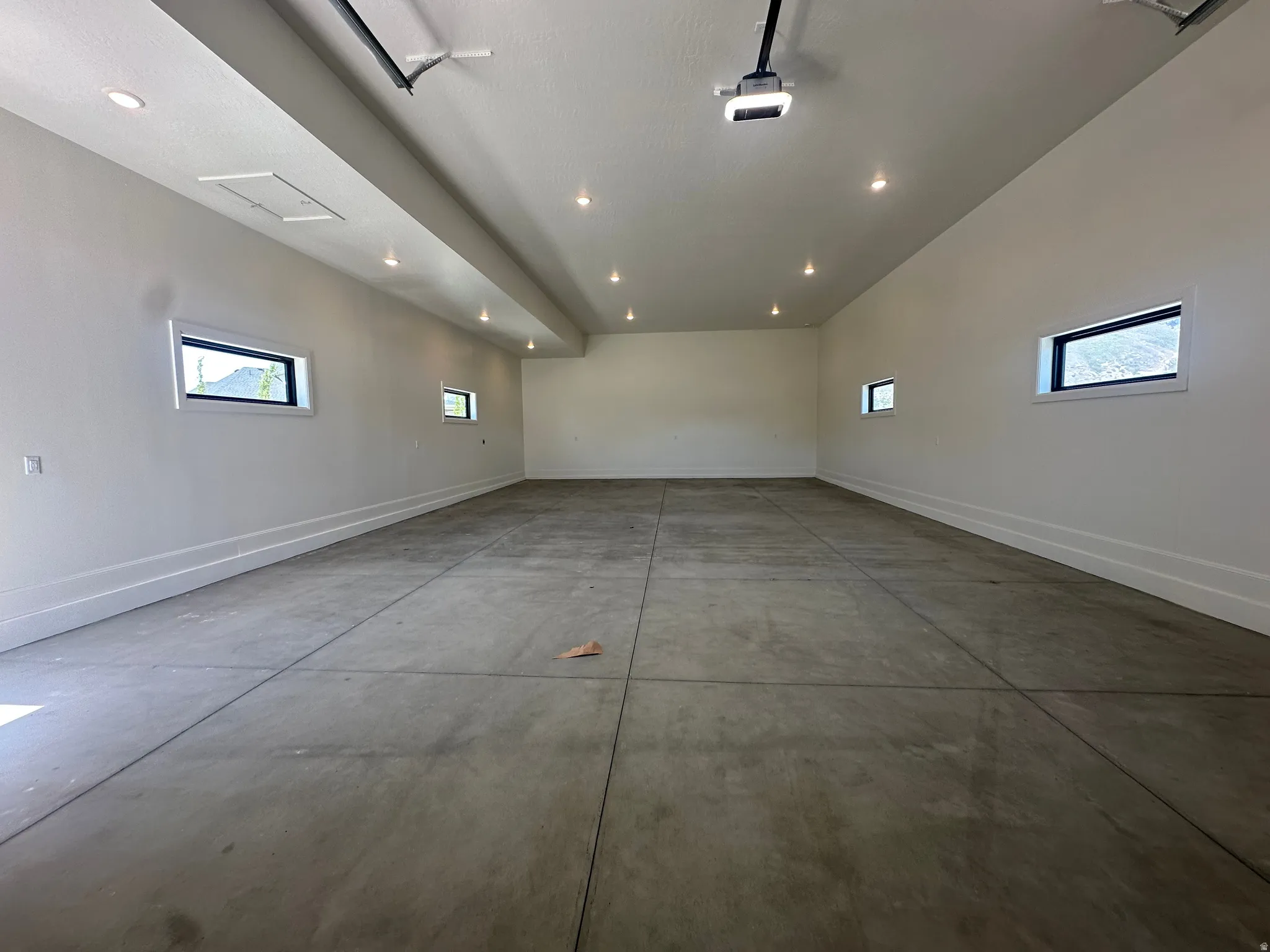 Oversized finished garage, recessed lighting, white walls, and multiple transom windows