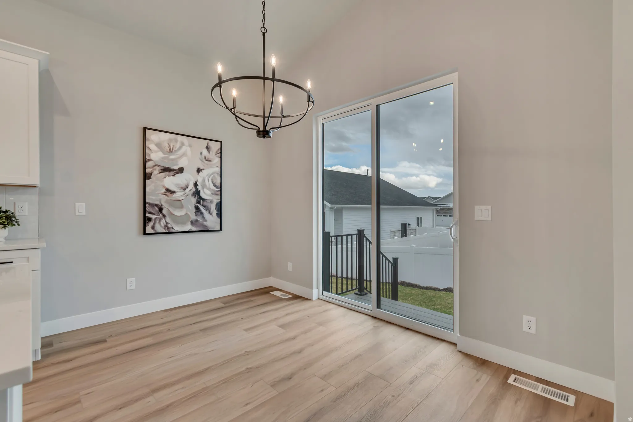 Unfurnished dining area with hanging lights, light wood finished floors, and lofted ceiling
