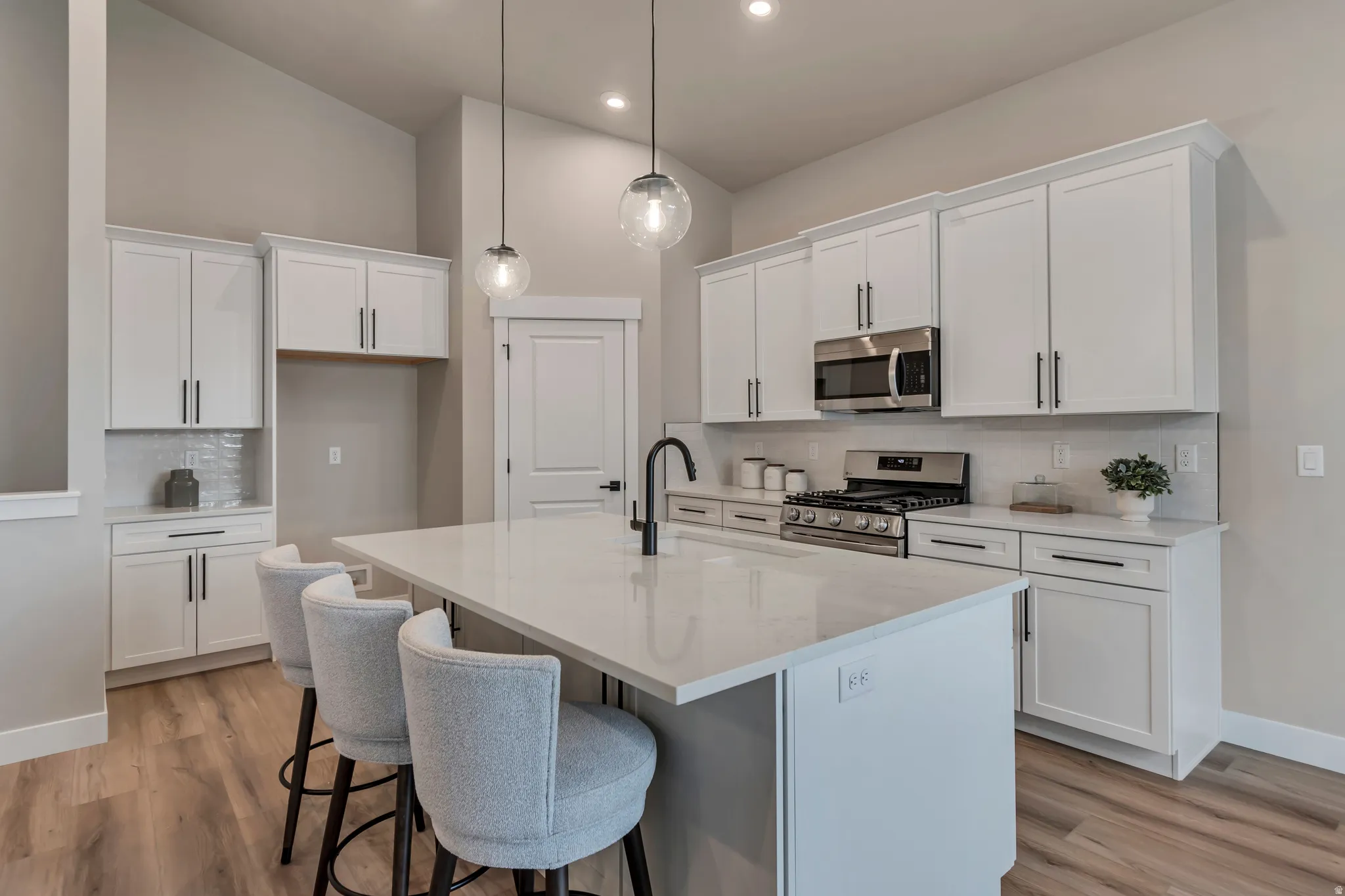 Kitchen featuring backsplash, white cabinets, stainless steel appliances, a breakfast bar area, and vaulted ceiling