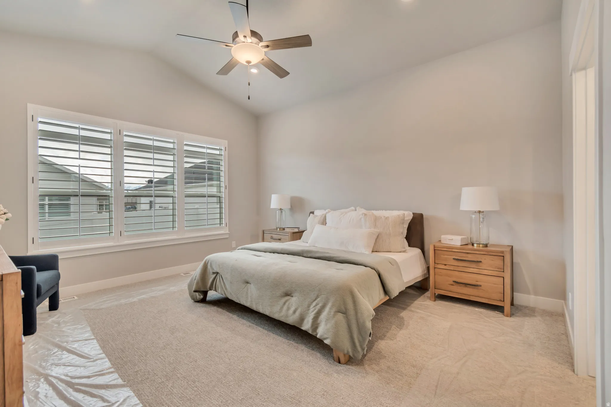 Bedroom with vaulted ceiling, a ceiling fan, and carpet