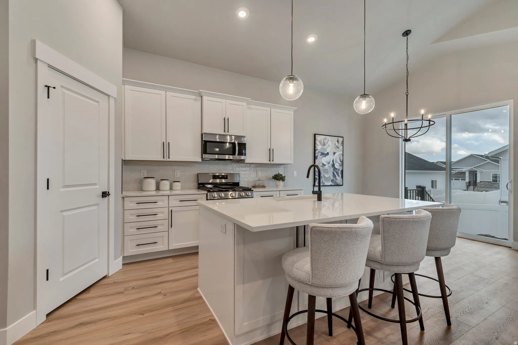 Kitchen featuring white cabinets, stainless steel appliances, a kitchen island with sink, a kitchen bar, and lofted ceiling