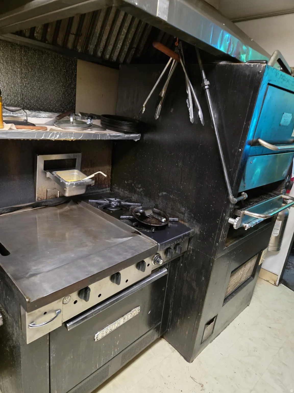 Kitchen with range hood, dark countertops, stainless steel range, and light marble finish flooring