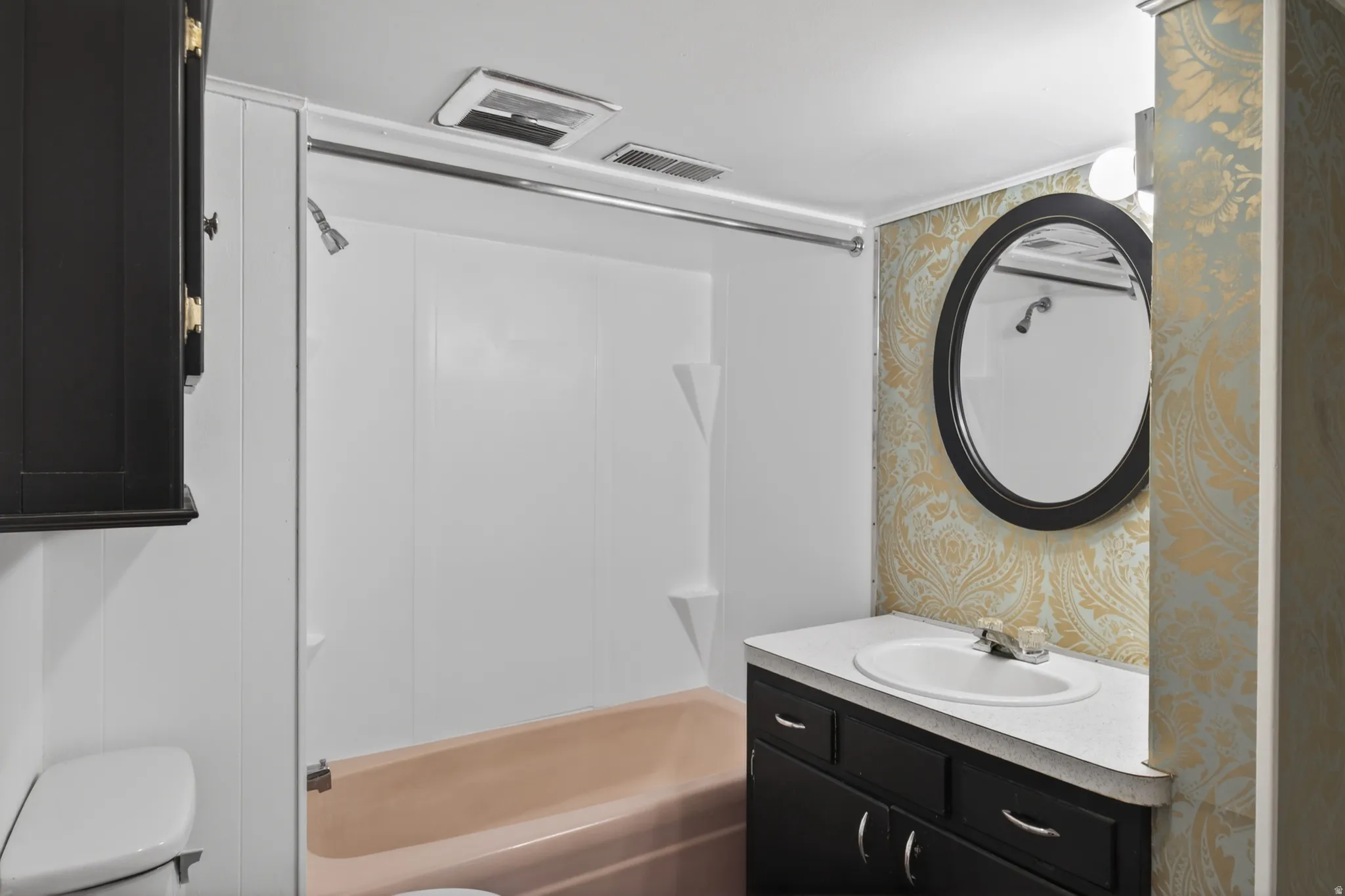 Bathroom with wallpapered walls, vanity, and shower / bath combination