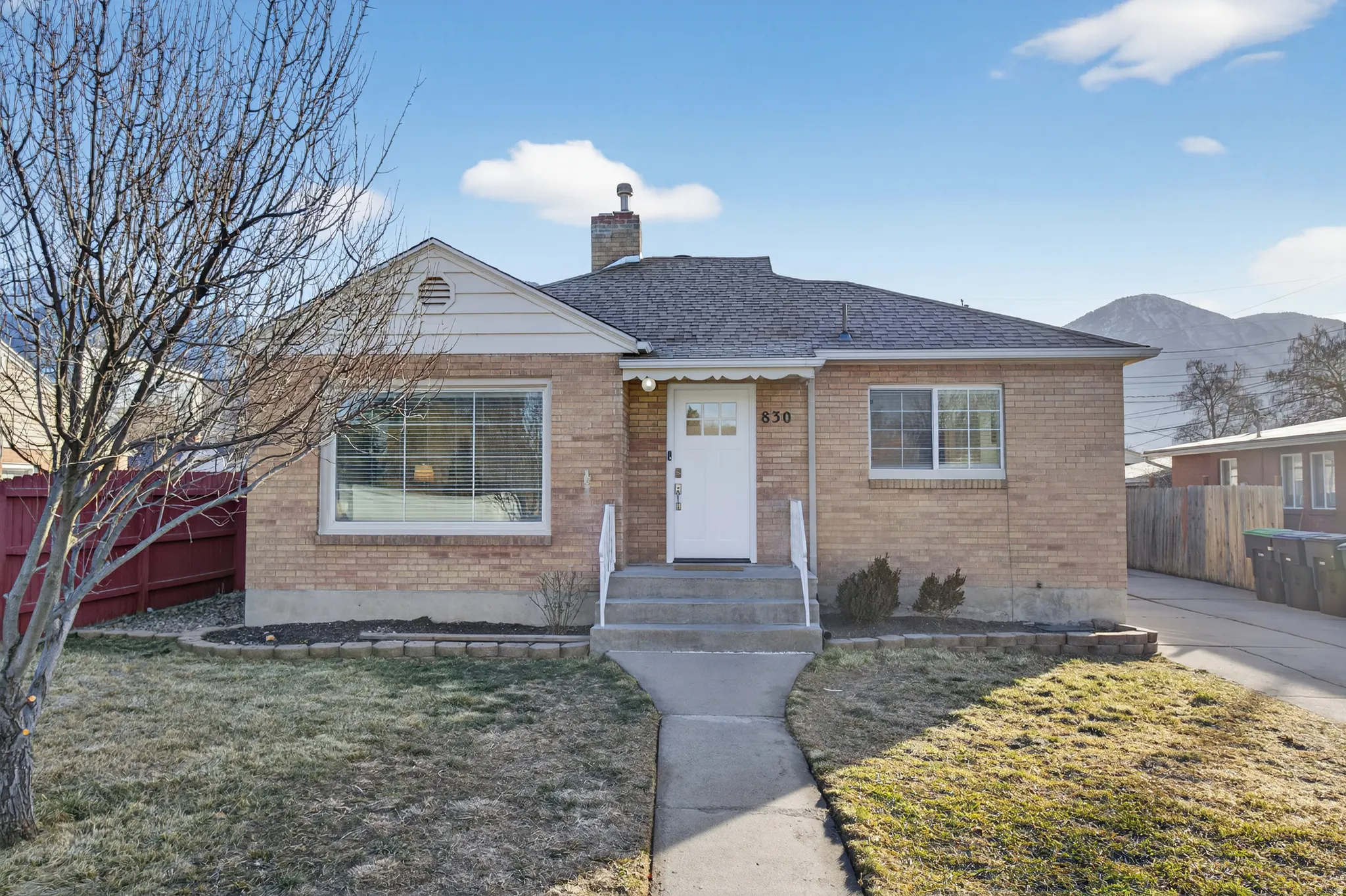 View of front of house featuring brick siding, a chimney, a shingled roof, and a mountain view