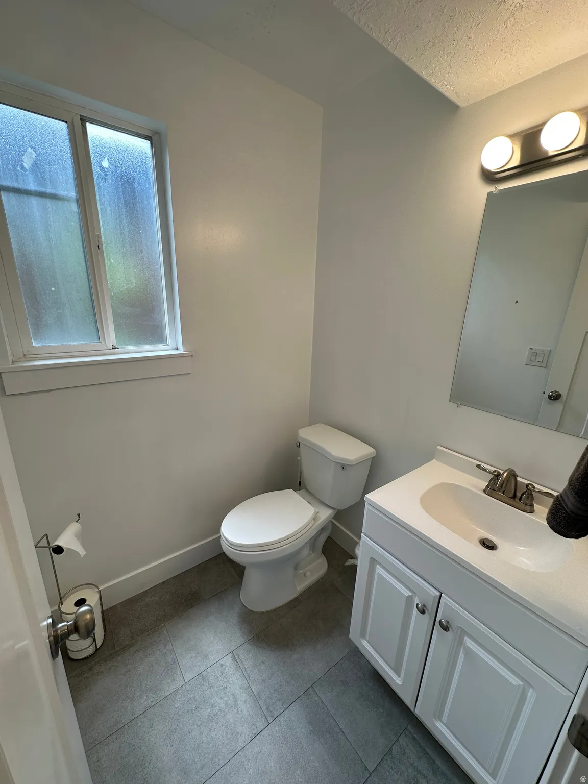 Bathroom featuring vanity, dark tile patterned floors, and a textured ceiling