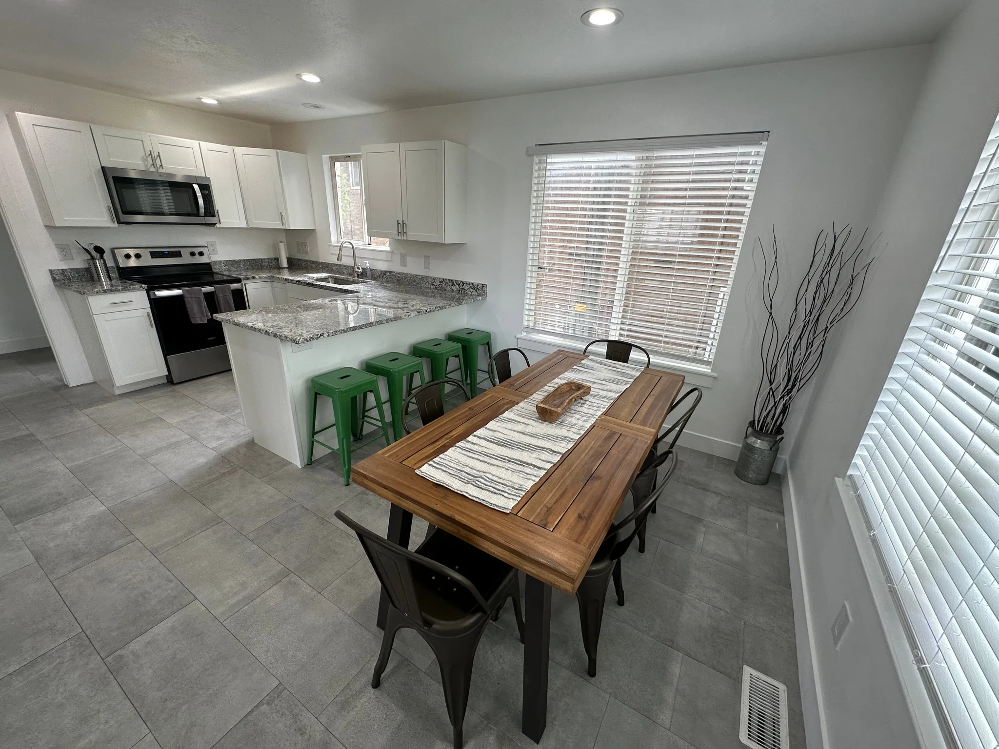 Kitchen with light stone counters, stainless steel appliances, white cabinetry, a peninsula, and a breakfast bar area