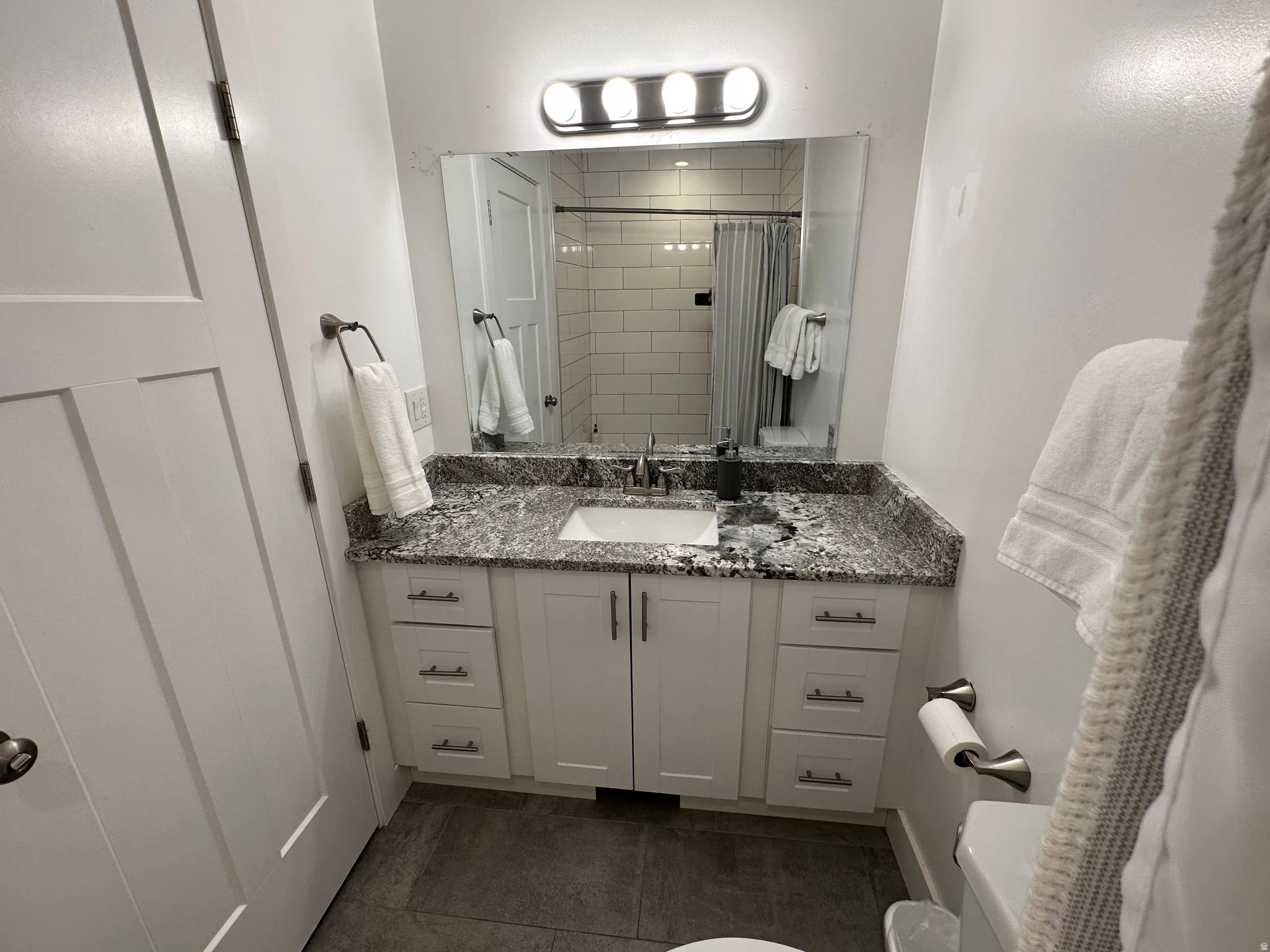 Bathroom with a shower with shower curtain, vanity, and dark tile patterned flooring