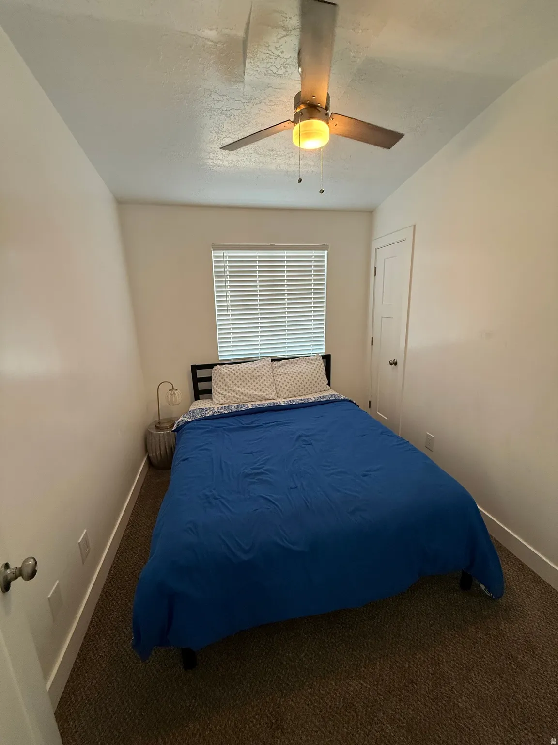 Carpeted bedroom with a ceiling fan and vaulted ceiling