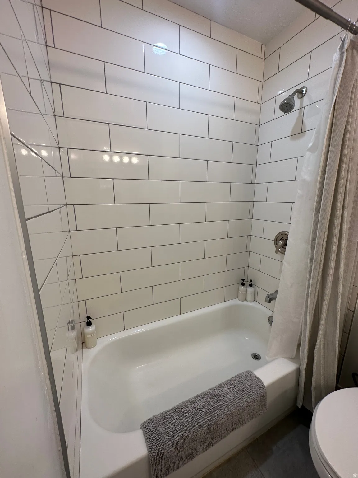 Bathroom with shower / bathtub combination with curtain and toilet