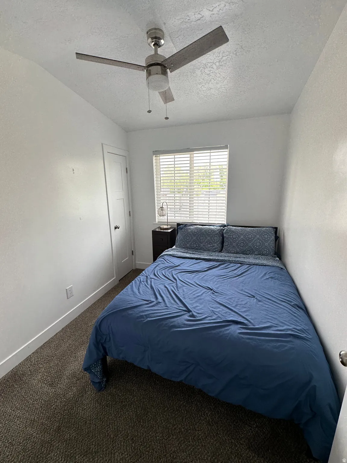 Bedroom featuring dark carpet, a textured ceiling, and ceiling fan