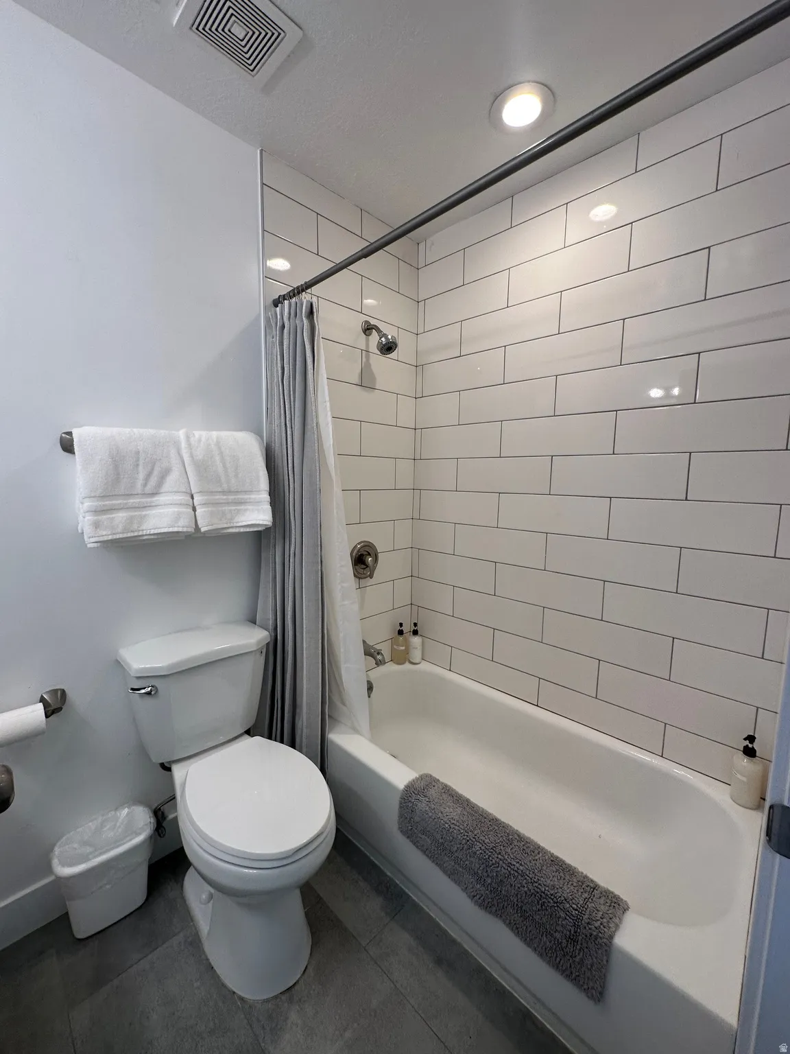 Bathroom featuring shower / tub combo and dark tile patterned flooring