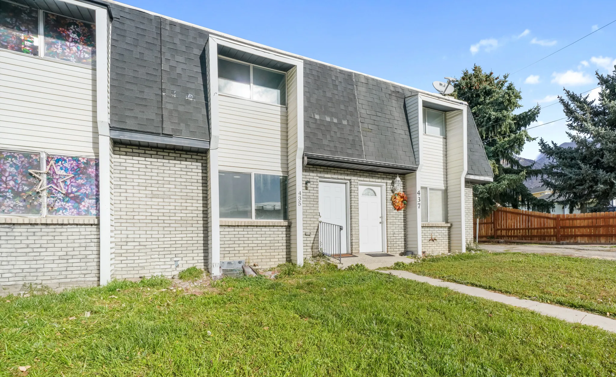 View of front of house featuring brick siding, a shingled roof, and mansard roof