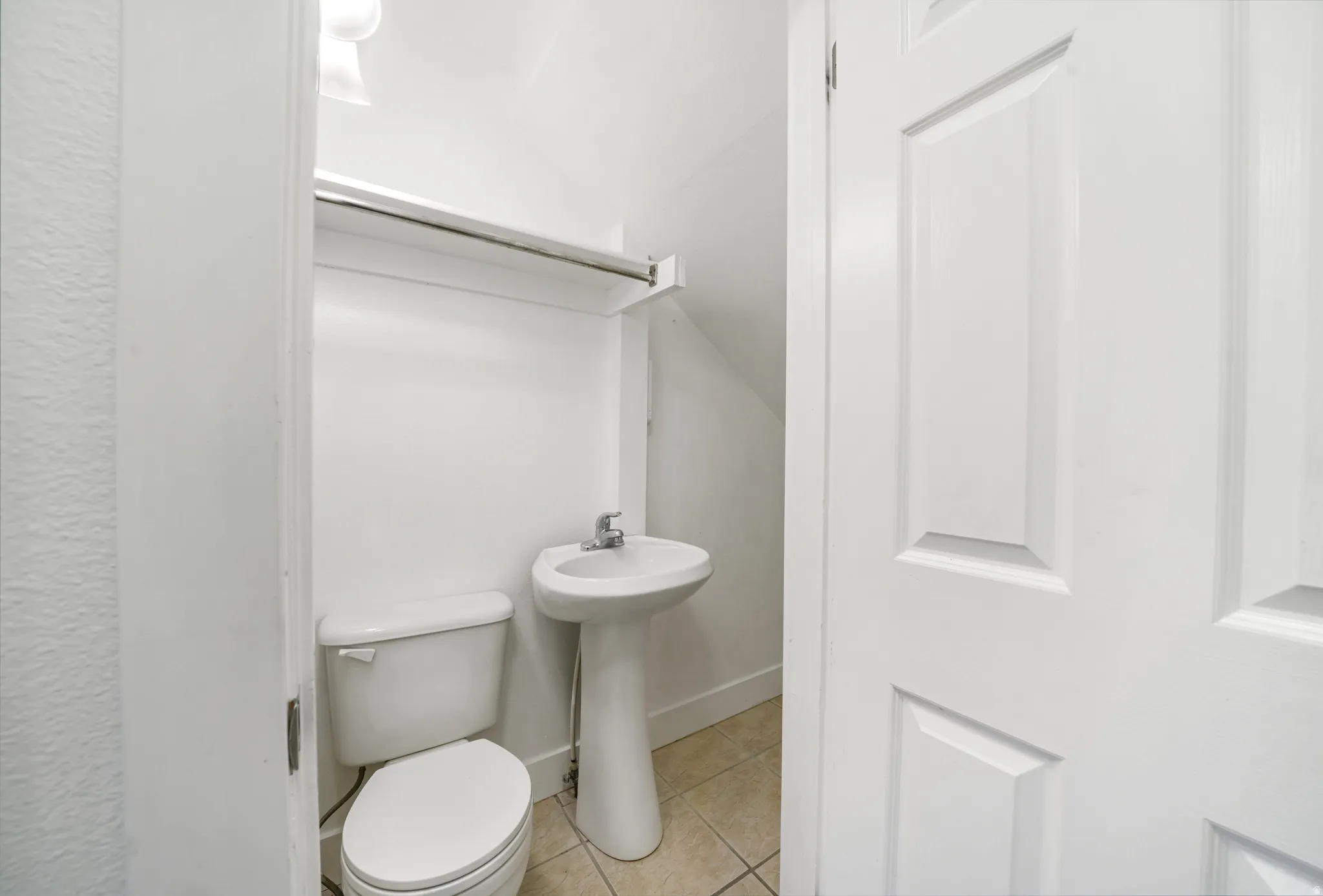 Half bath featuring toilet and light tile patterned flooring