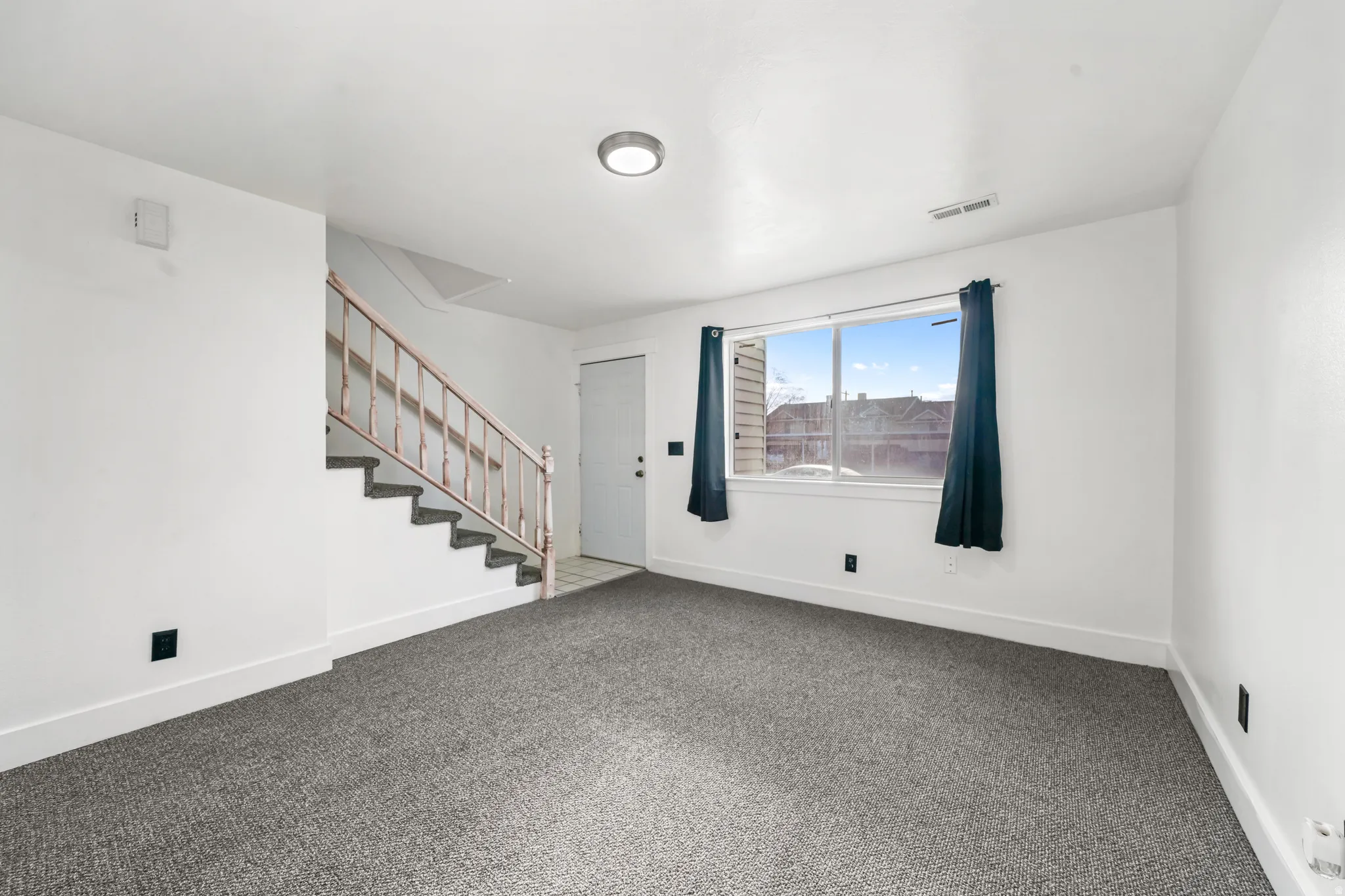 Carpeted empty room featuring stairs and baseboards