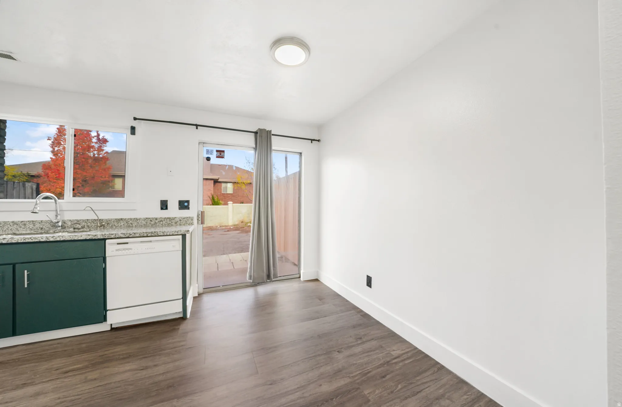 Kitchen with dishwasher, dark wood-style flooring, green cabinets, and light stone countertops