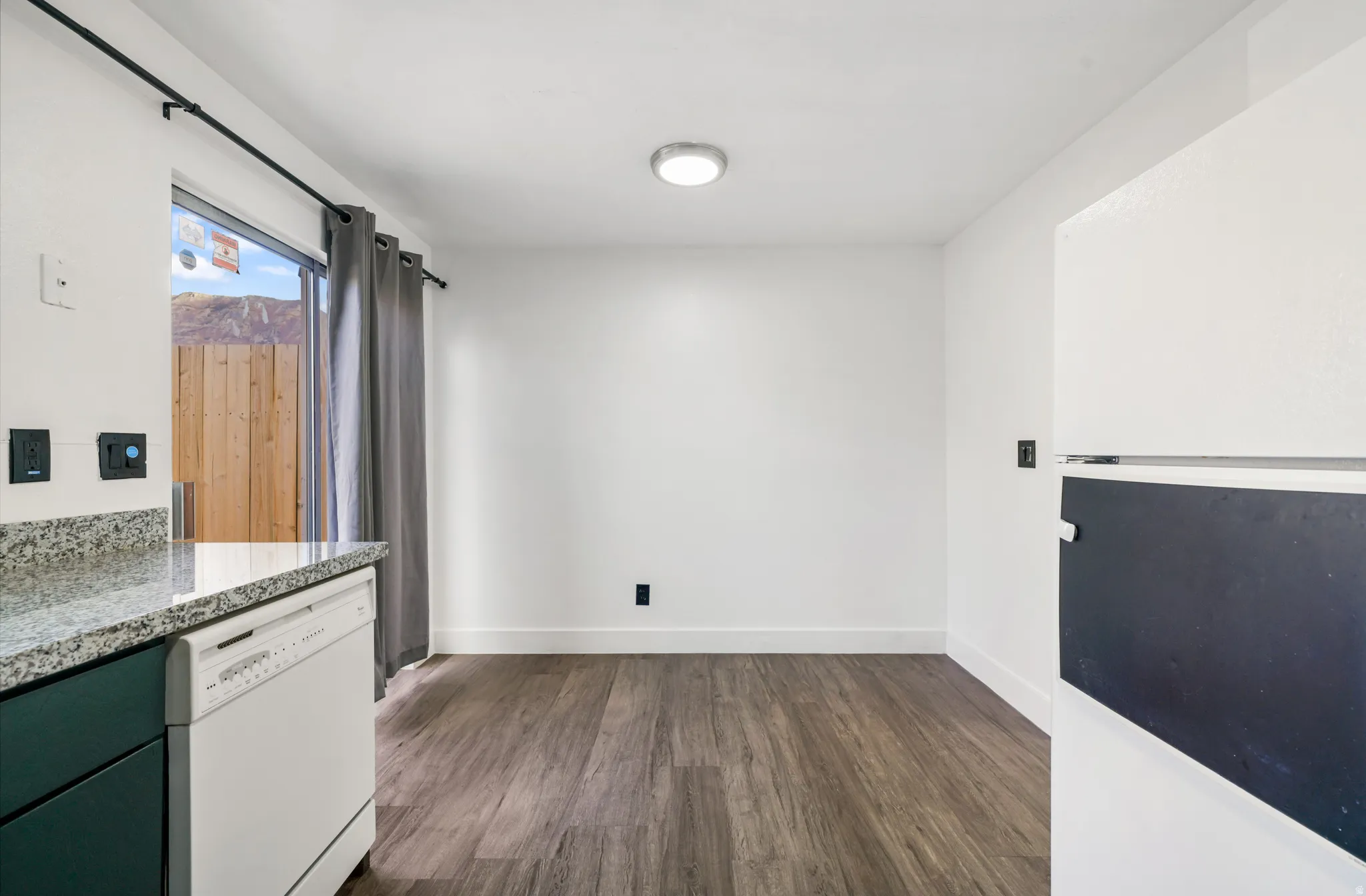 Unfurnished dining area featuring dark wood-type flooring and baseboards