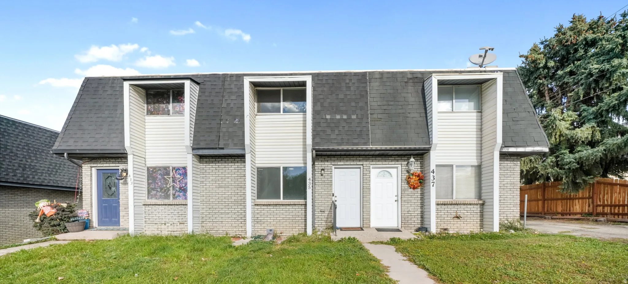 View of front of home featuring mansard roof, a shingled roof, and brick siding