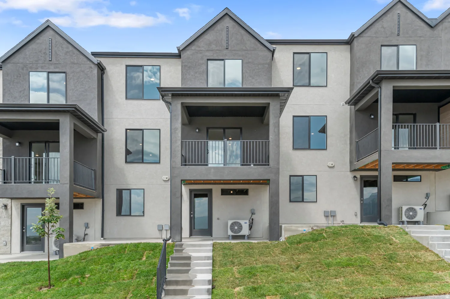 Contemporary home with stucco siding, a patio area, a balcony, and a front lawn