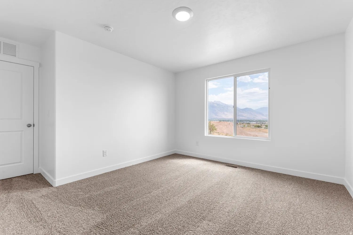Unfurnished room featuring a mountain view and light carpet