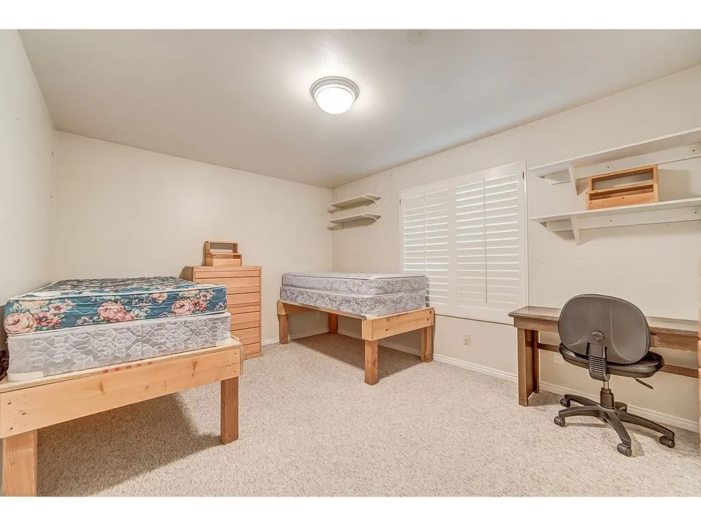 Bedroom with light colored carpet and an office area