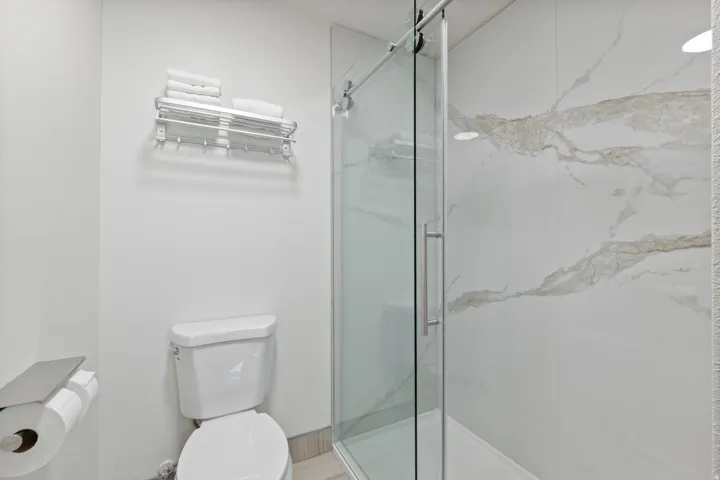 Full bathroom featuring toilet and a marble finish shower