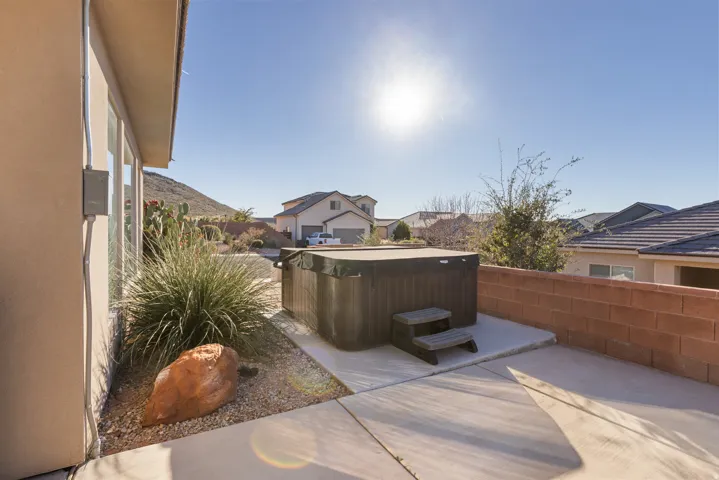 View of patio with a hot tub and a residential view