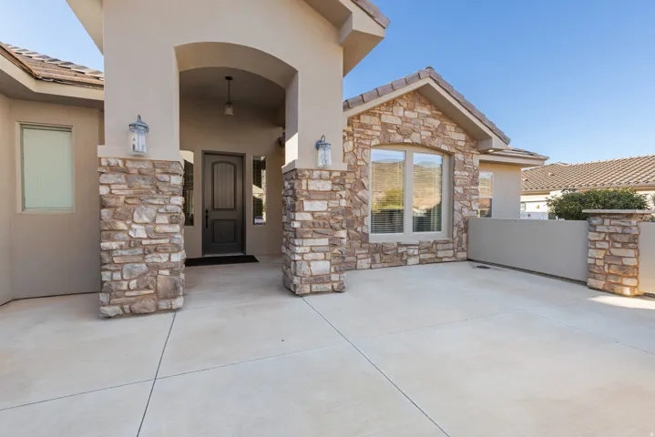 Doorway to property with stone siding, stucco siding, and a tile roof