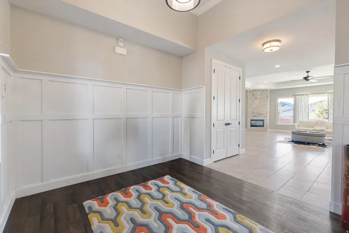 Corridor with a decorative wall, dark wood-type flooring, and a wainscoted wall
