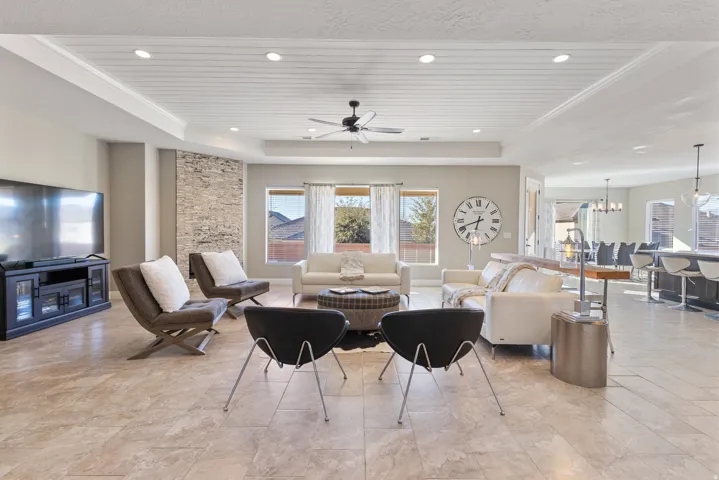Living room featuring a ceiling fan, a chandelier, a tray ceiling, and wooden ceiling