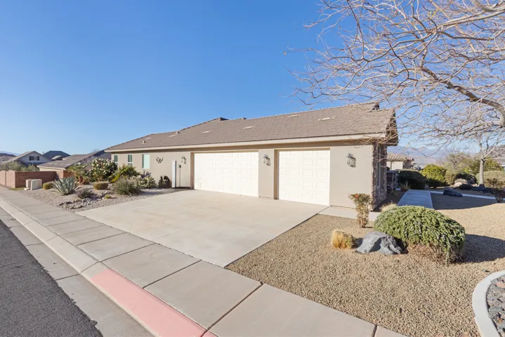 View of front of house with stucco siding, concrete driveway, and an attached garage