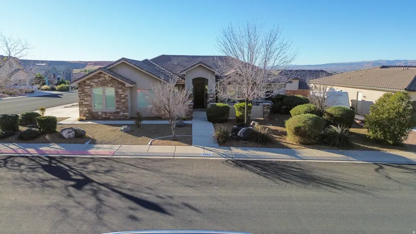 View of front of home with stucco siding, stone siding, and a tile roof