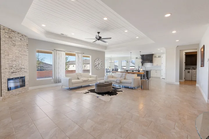 Living area with a ceiling fan, a fireplace, a tray ceiling, washing machine and clothes dryer, and wooden ceiling