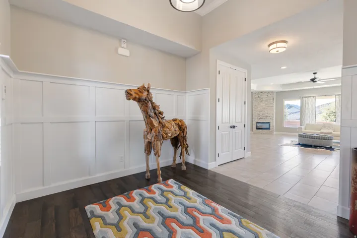Hall featuring a decorative wall, wood finished floors, and wainscoting