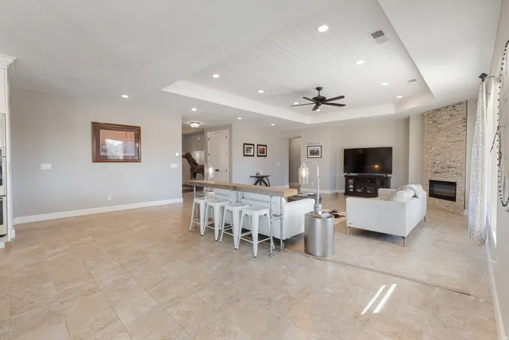 Living area featuring a raised ceiling, a fireplace, ceiling fan, recessed lighting, and a barn door