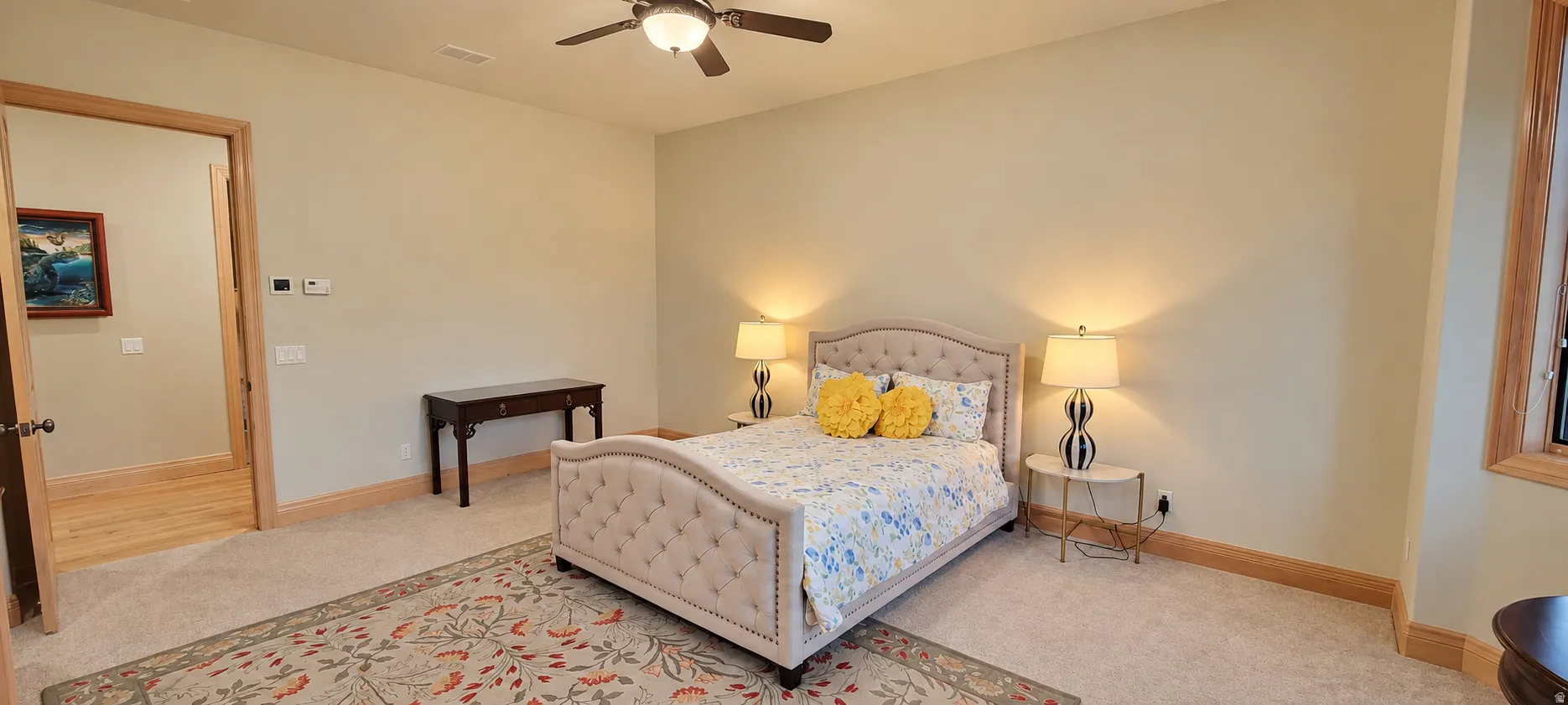 Carpeted room with a ceiling fan, light-colored walls, and wood trim around the doorway