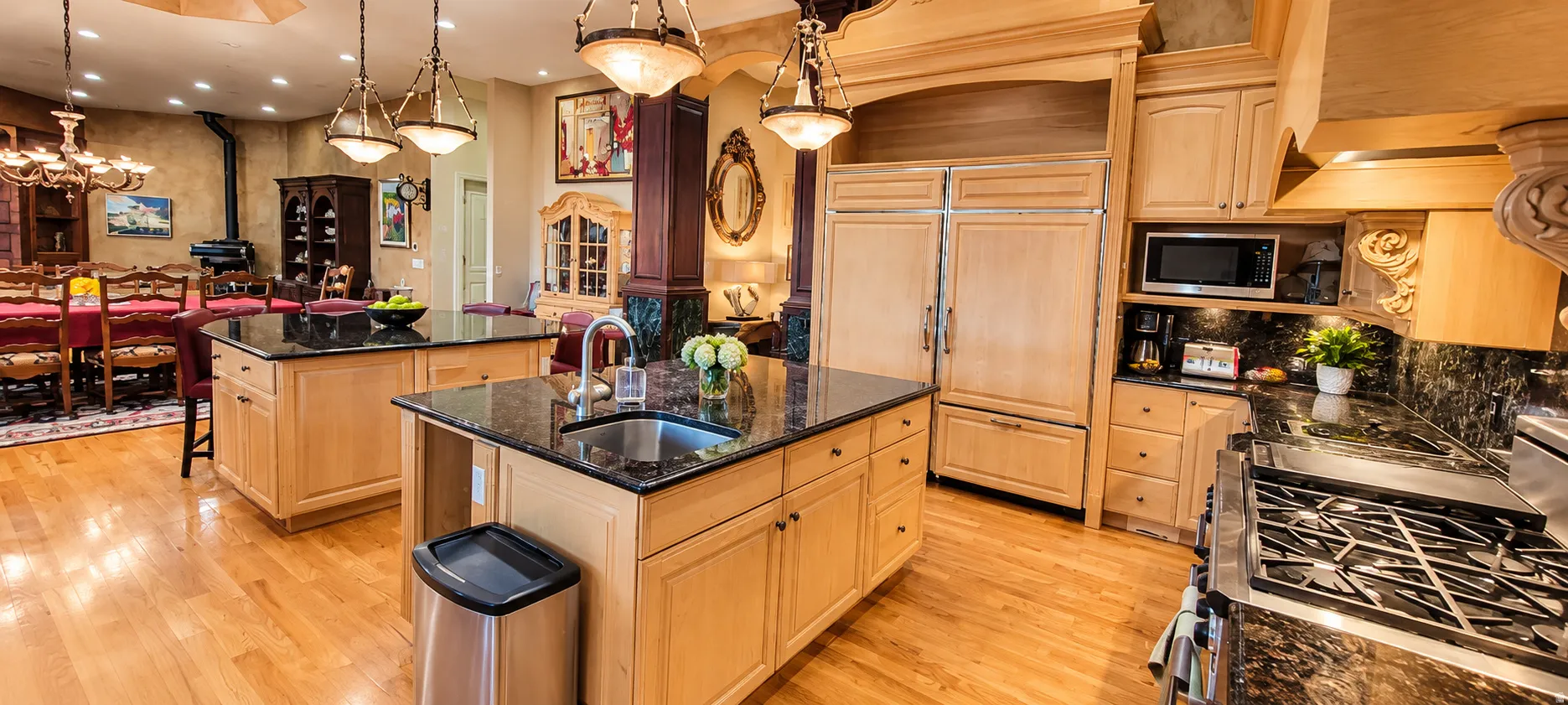 Kitchen featuring natural wood cabinetry, dark stone countertops, stainless steel appliances, and wood-finish flooring