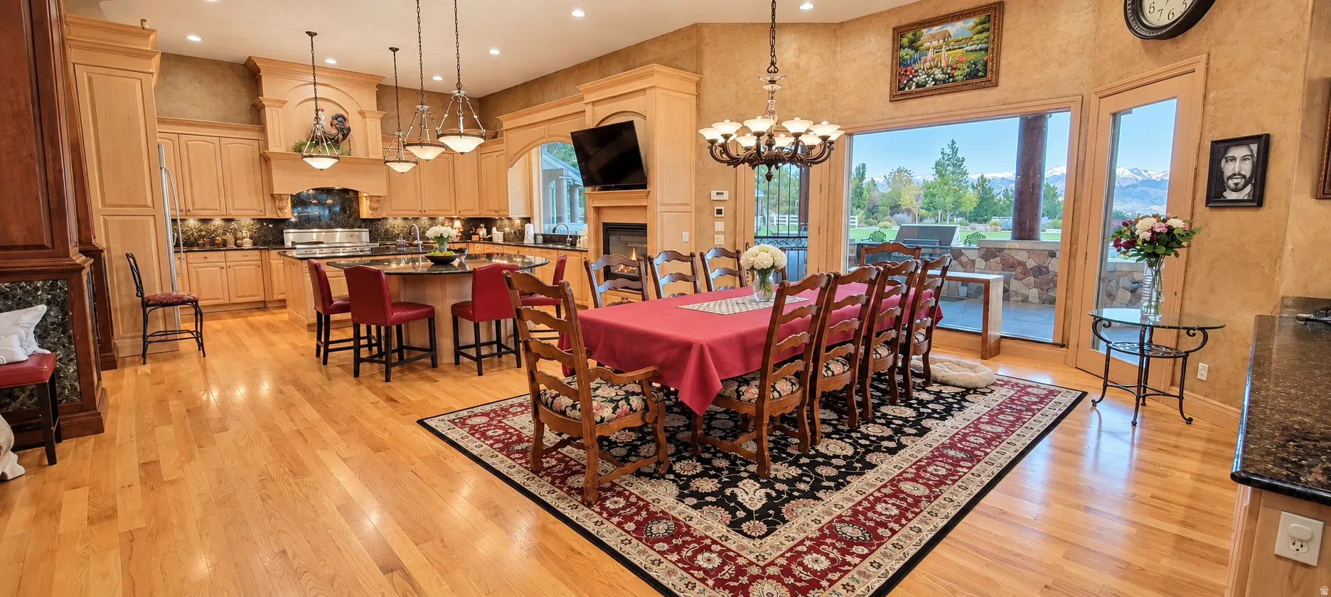 Hardwood flooring throughout, a kitchen with light wood cabinetry, a central island with bar seating, and recessed lighting