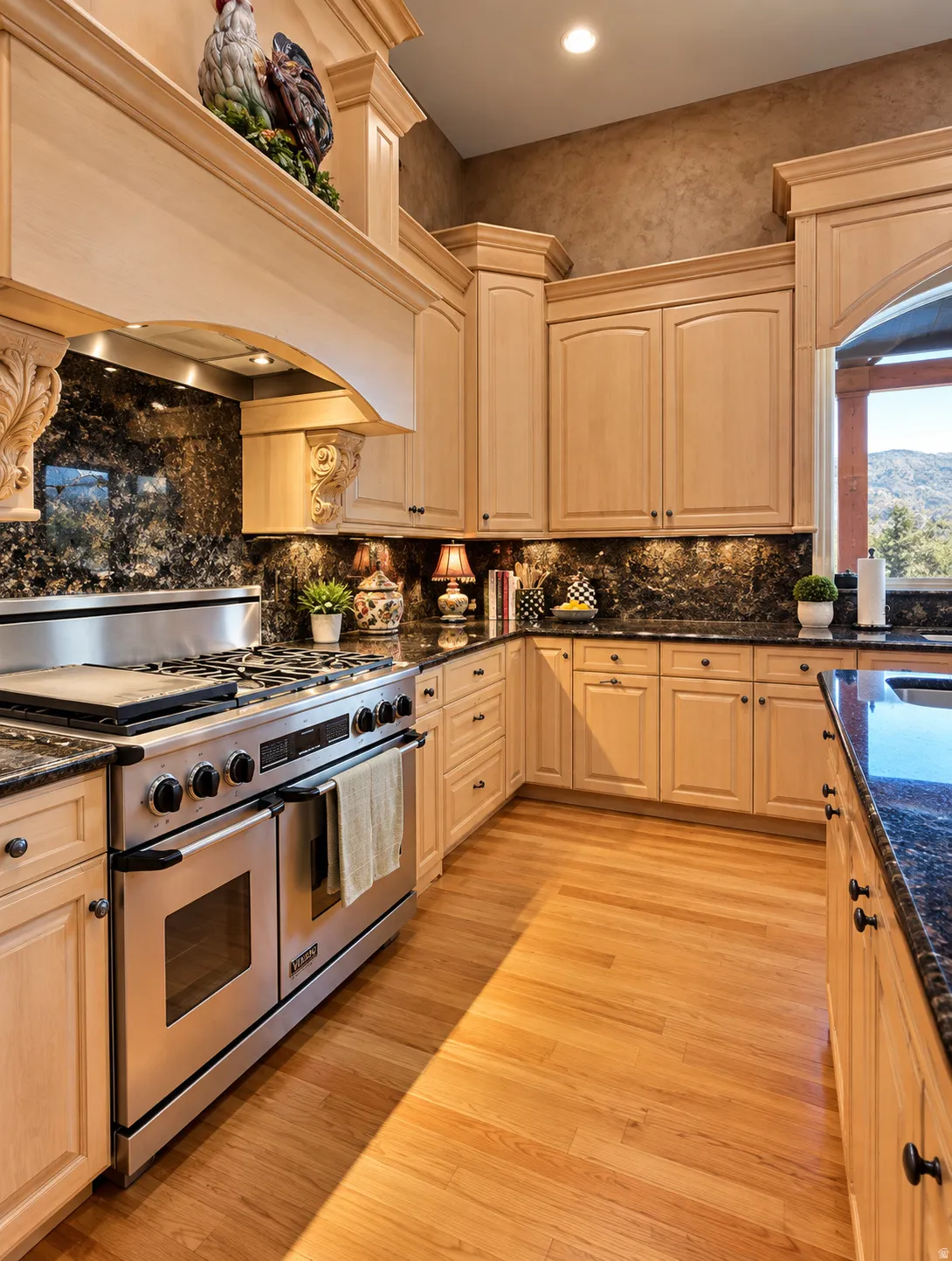 Kitchen featuring light wood cabinetry, dark granite countertops, stainless steel range, wood-finish flooring, and a decorative range hood