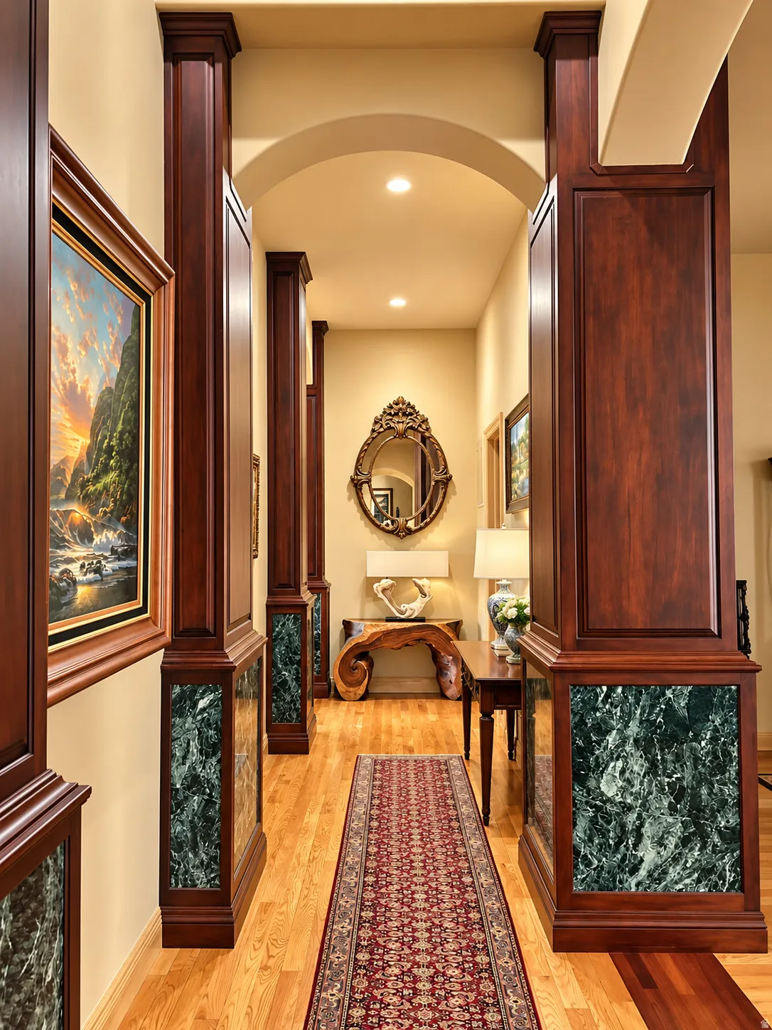 Archway entry with recessed lighting, wood-finish flooring, and wood-paneled columns featuring marble-look accents