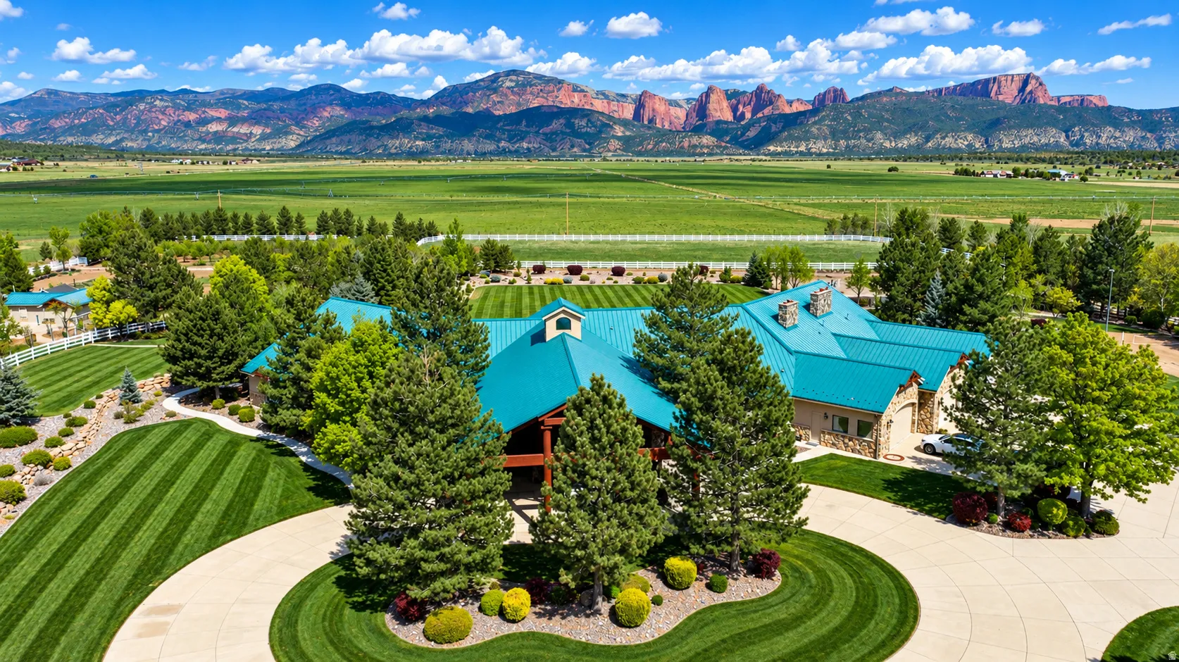 Expansive green metal roof, stone exterior detailing, and a circular driveway