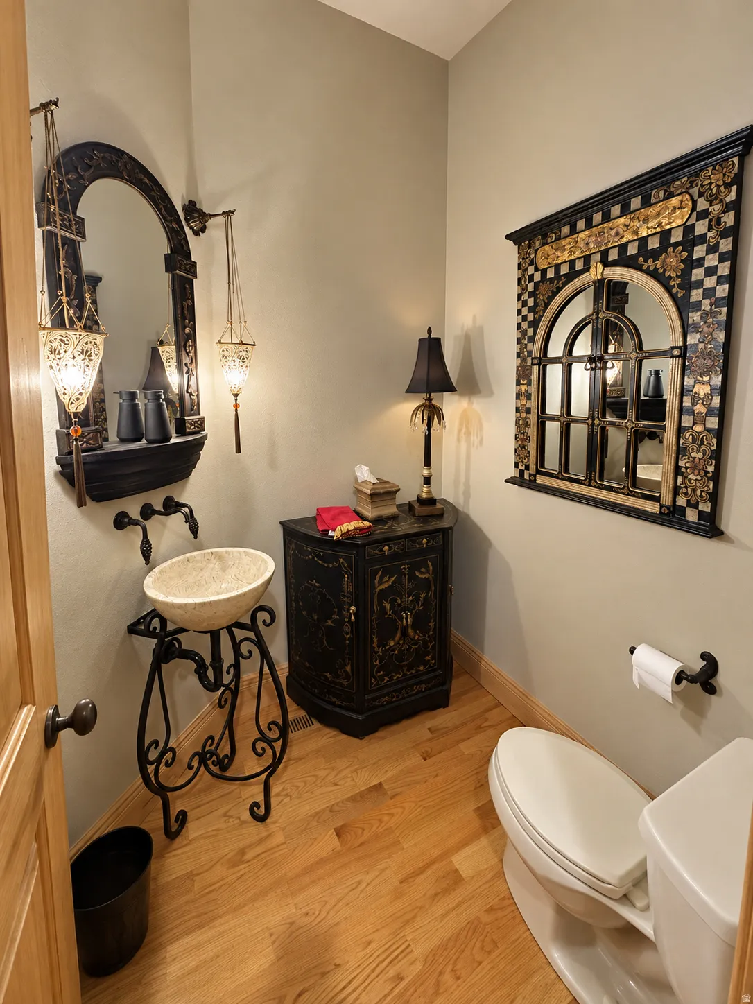 Hardwood flooring, pedestal sink with stone vessel, wall-mounted faucet, and decorative wall mirror